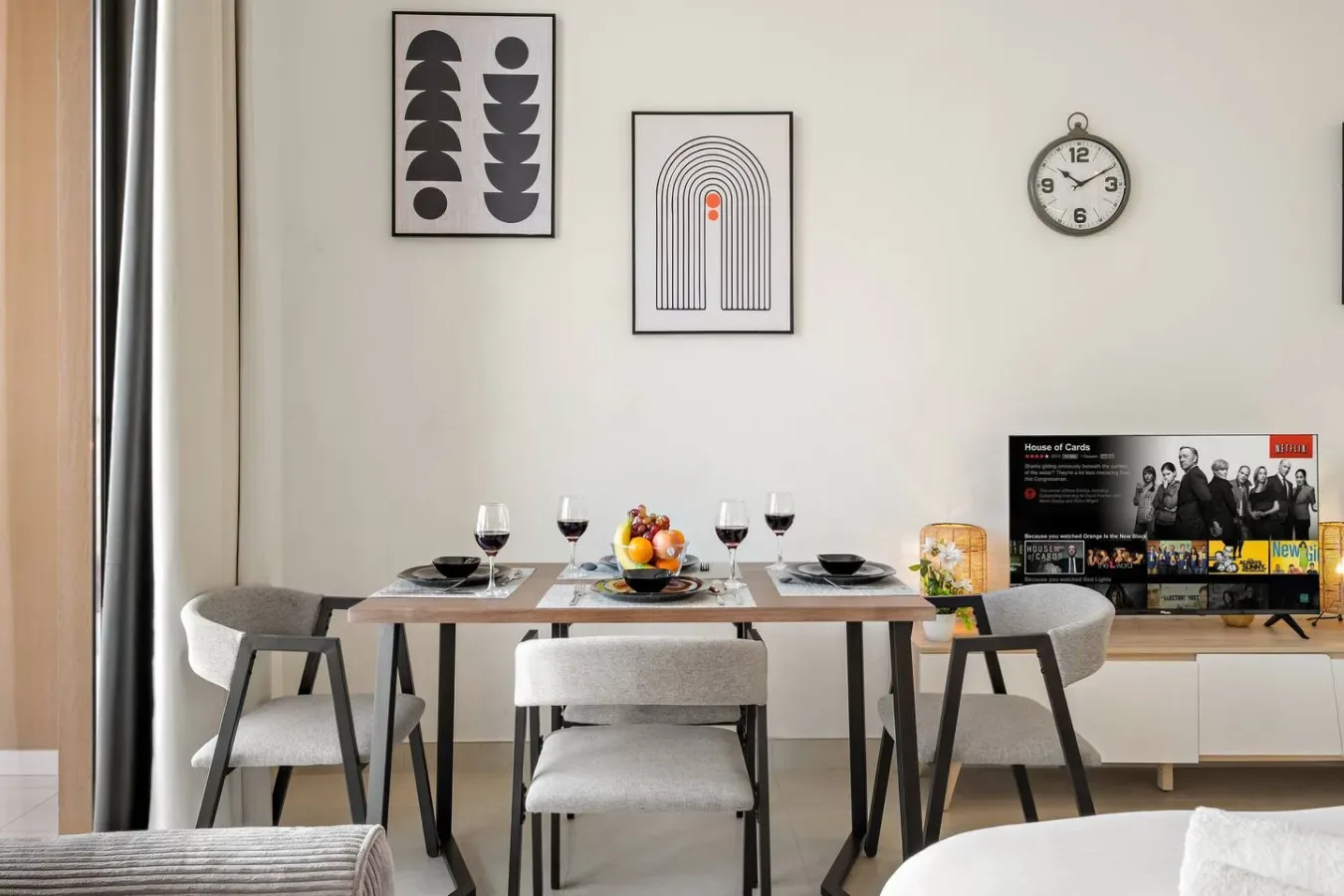 A dining area with a set table, wall art, and a clock.