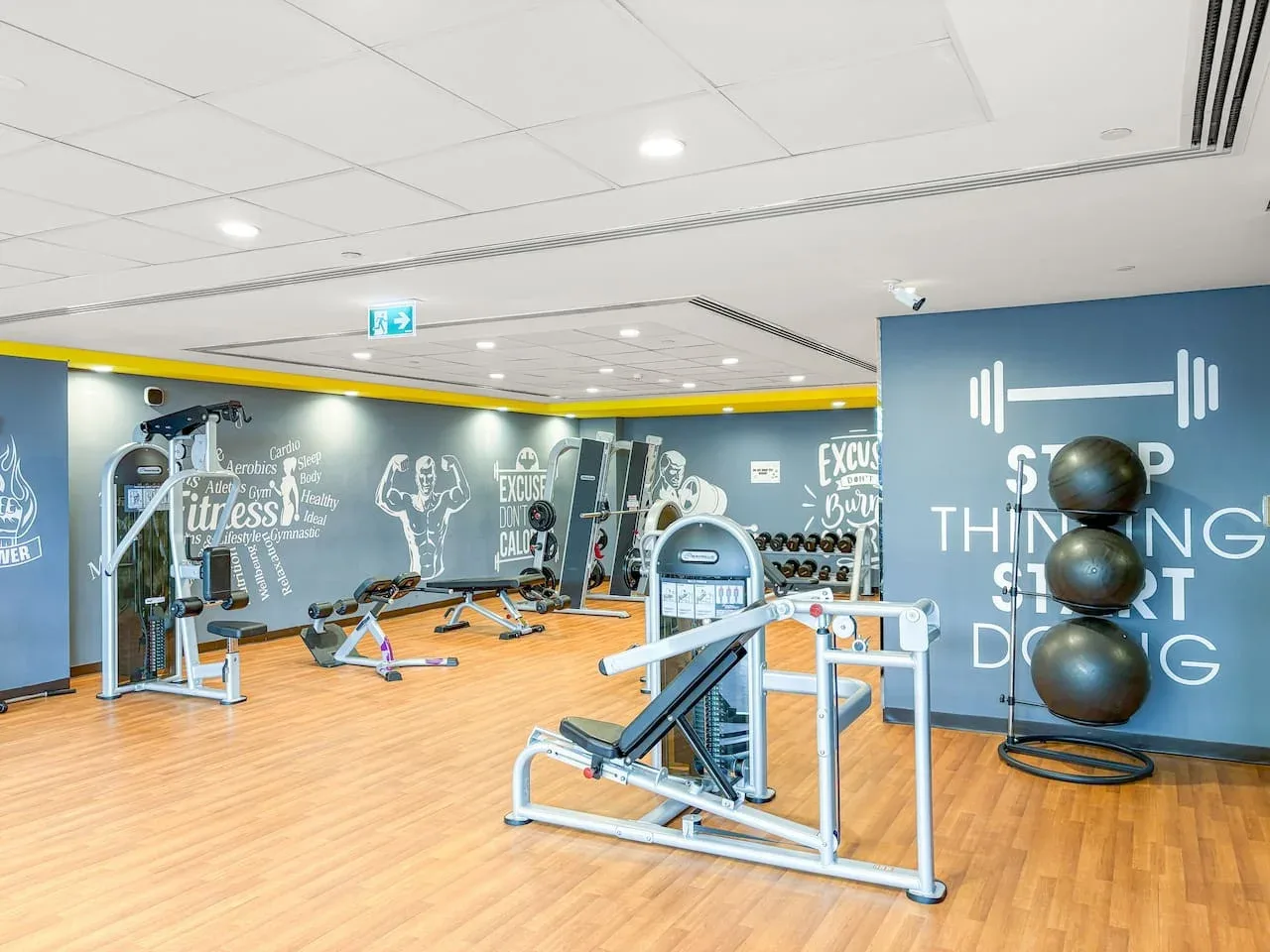 A gym with exercise machines and weight equipment against painted walls.