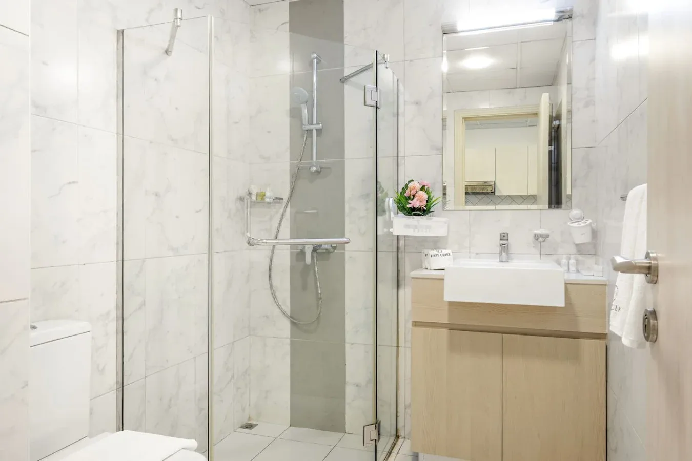 A bright bathroom with a glass shower and a sink vanity.