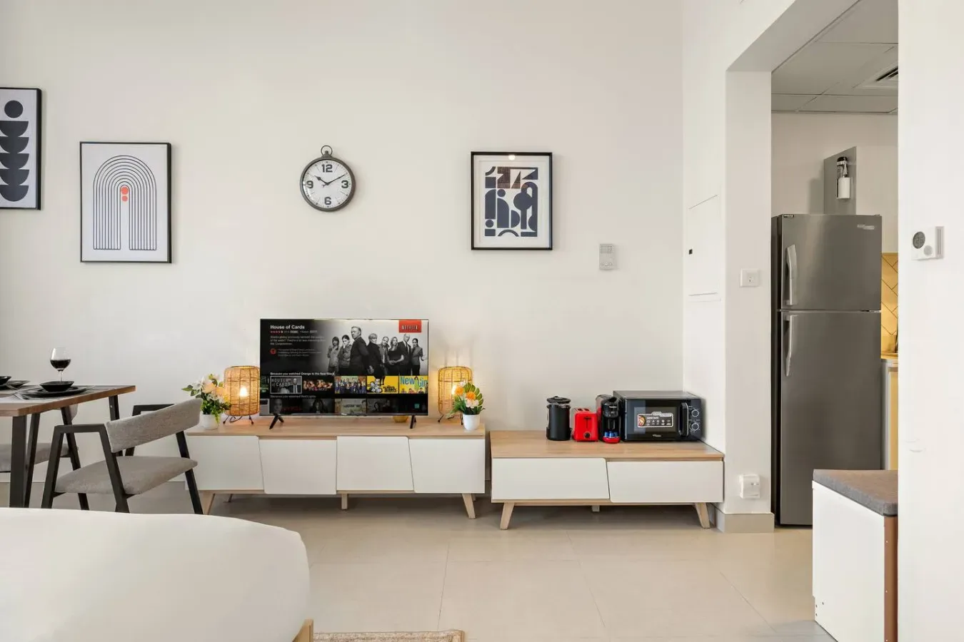 A bright living room with a television on a low console and a dining table.