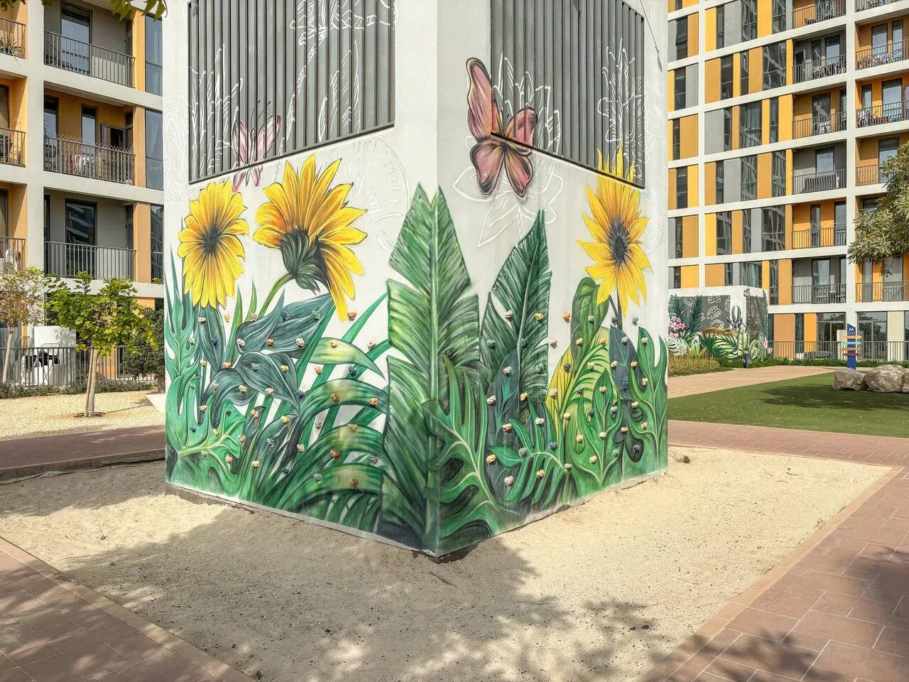 A colorful floral mural with sunflowers and a butterfly covers a courtyard structure.