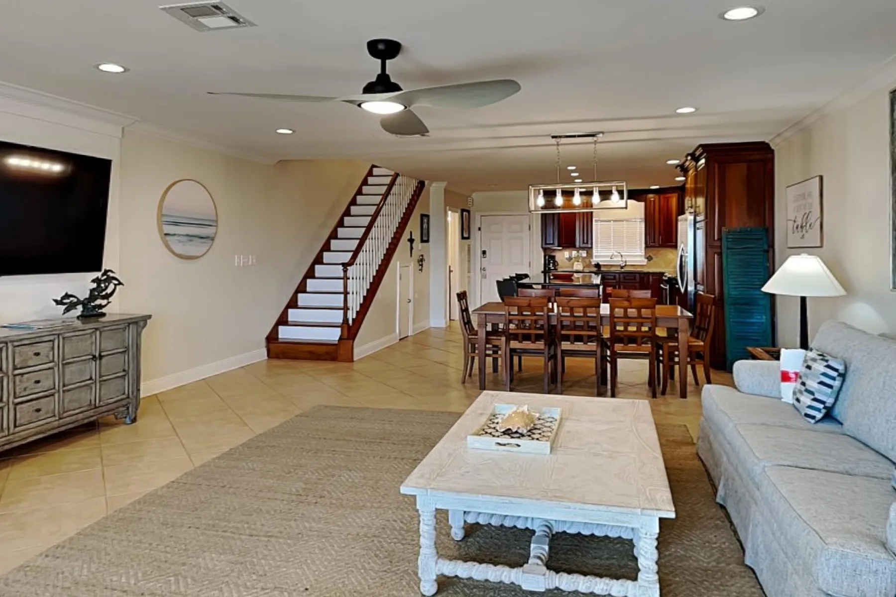 Un espacio abierto de sala y comedor con una escalera y una mesa de comedor.