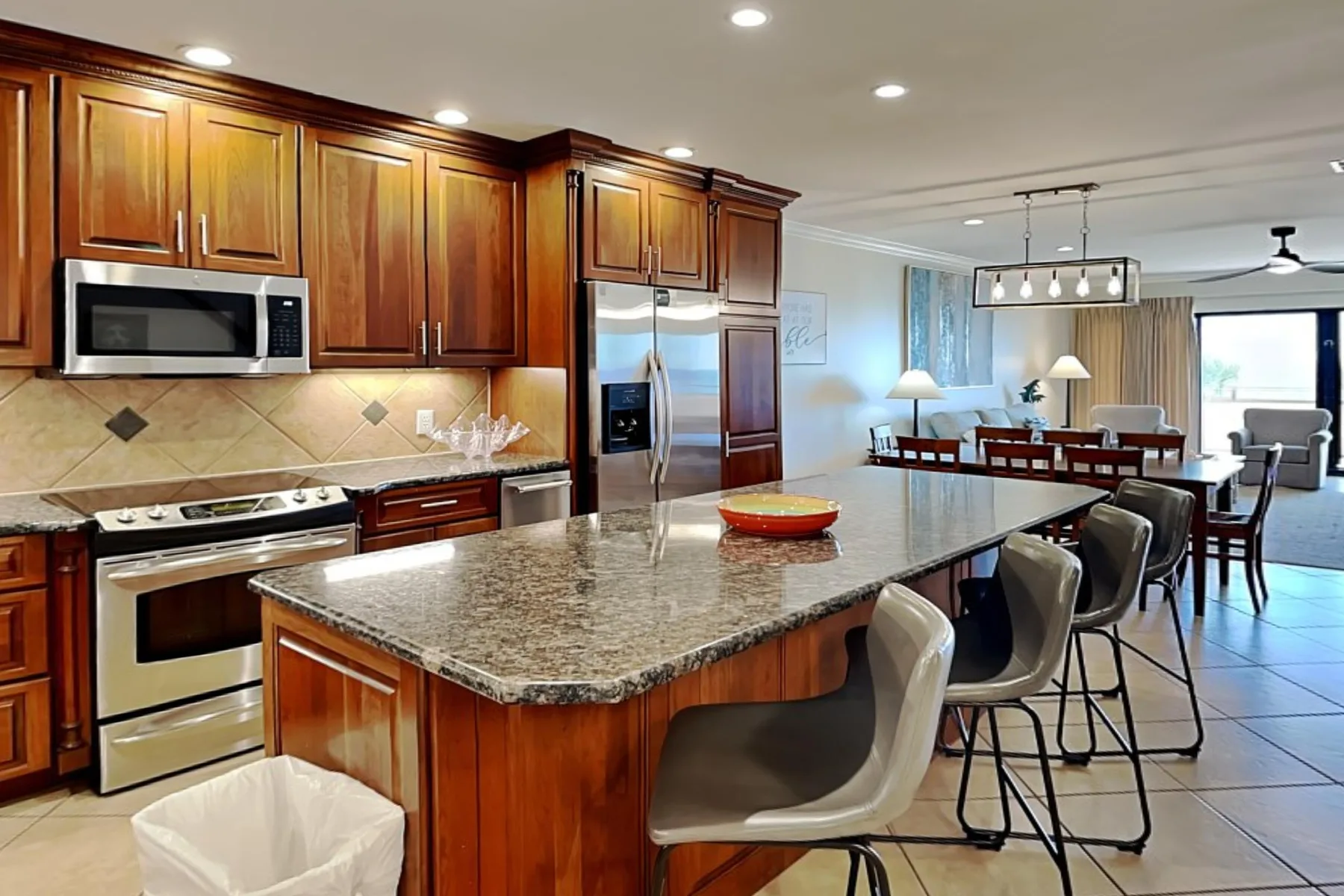 Una cocina amplia con una isla grande se abre a un comedor y una sala de estar.