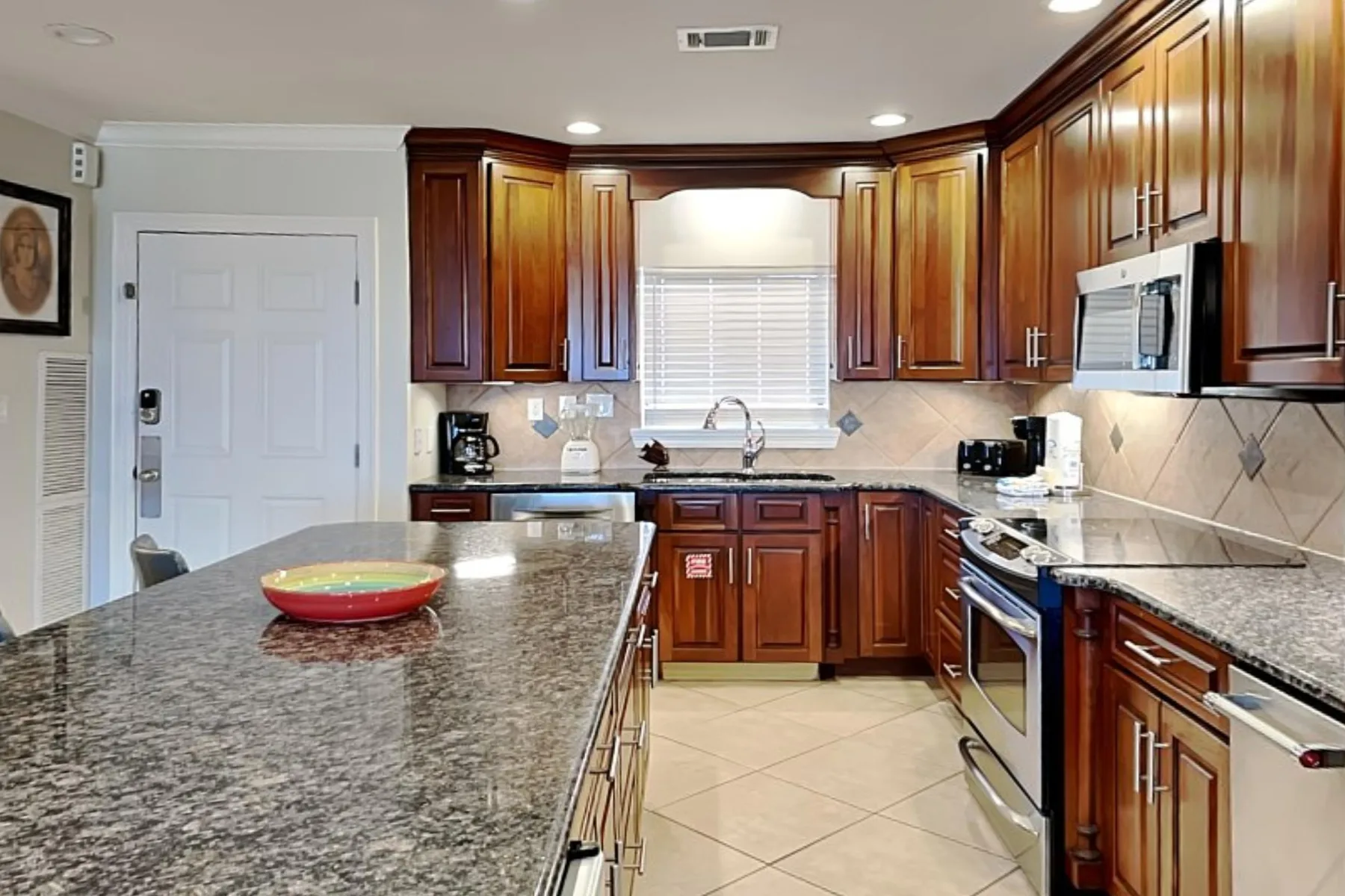 Una cocina con gabinetes de madera oscura, encimeras de piedra y una isla central.