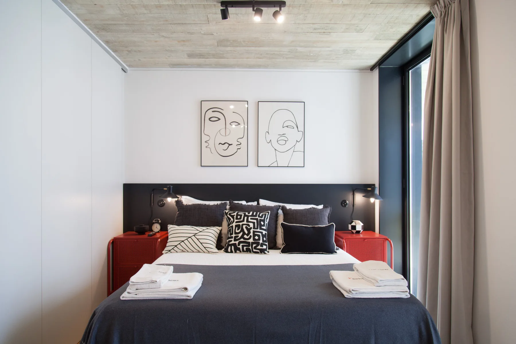 Un dormitorio con una cama bien hecha bajo dos dibujos enmarcados.