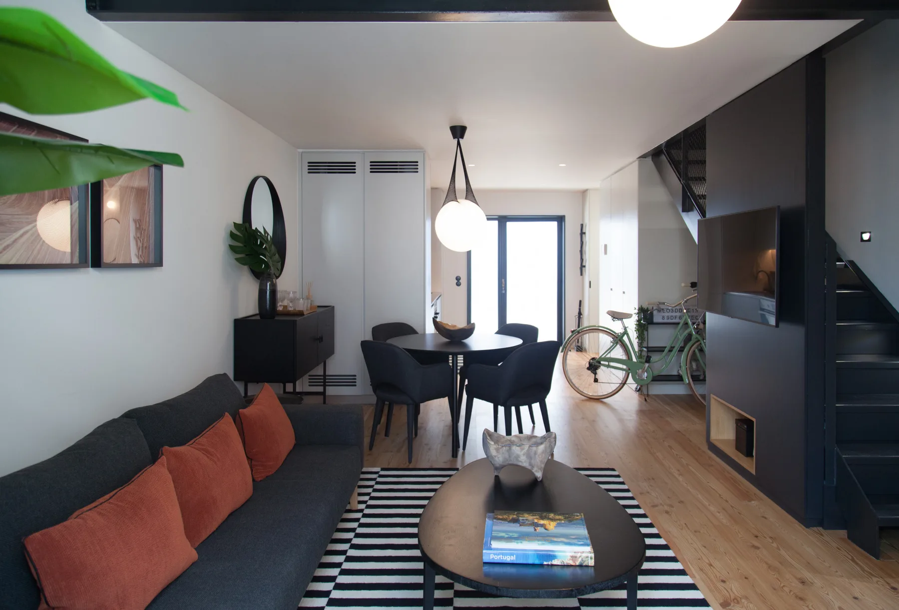 Una sala de estar moderna con sofá, mesa de comedor y escalera.