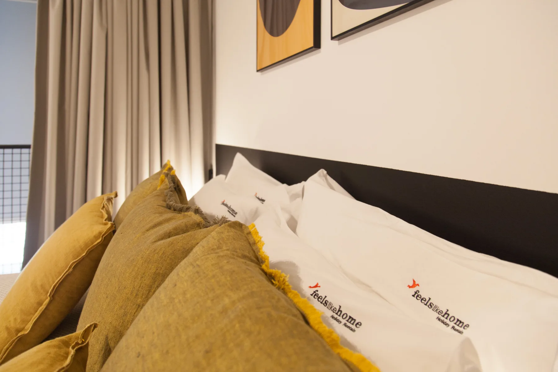Un dormitorio con una cama vestida con ropa blanca y cojines color mostaza.