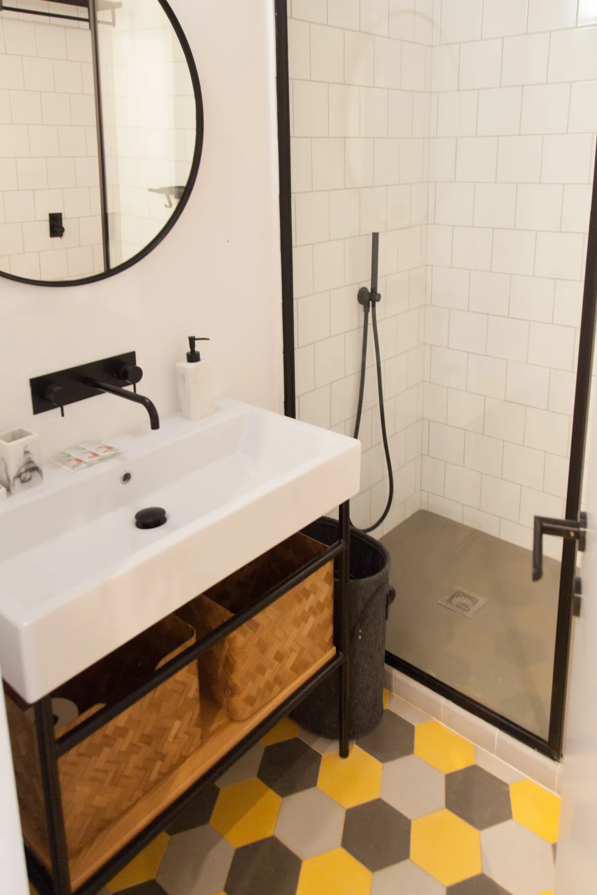 Un baño alicatado con lavabo, espejo redondo y ducha.
