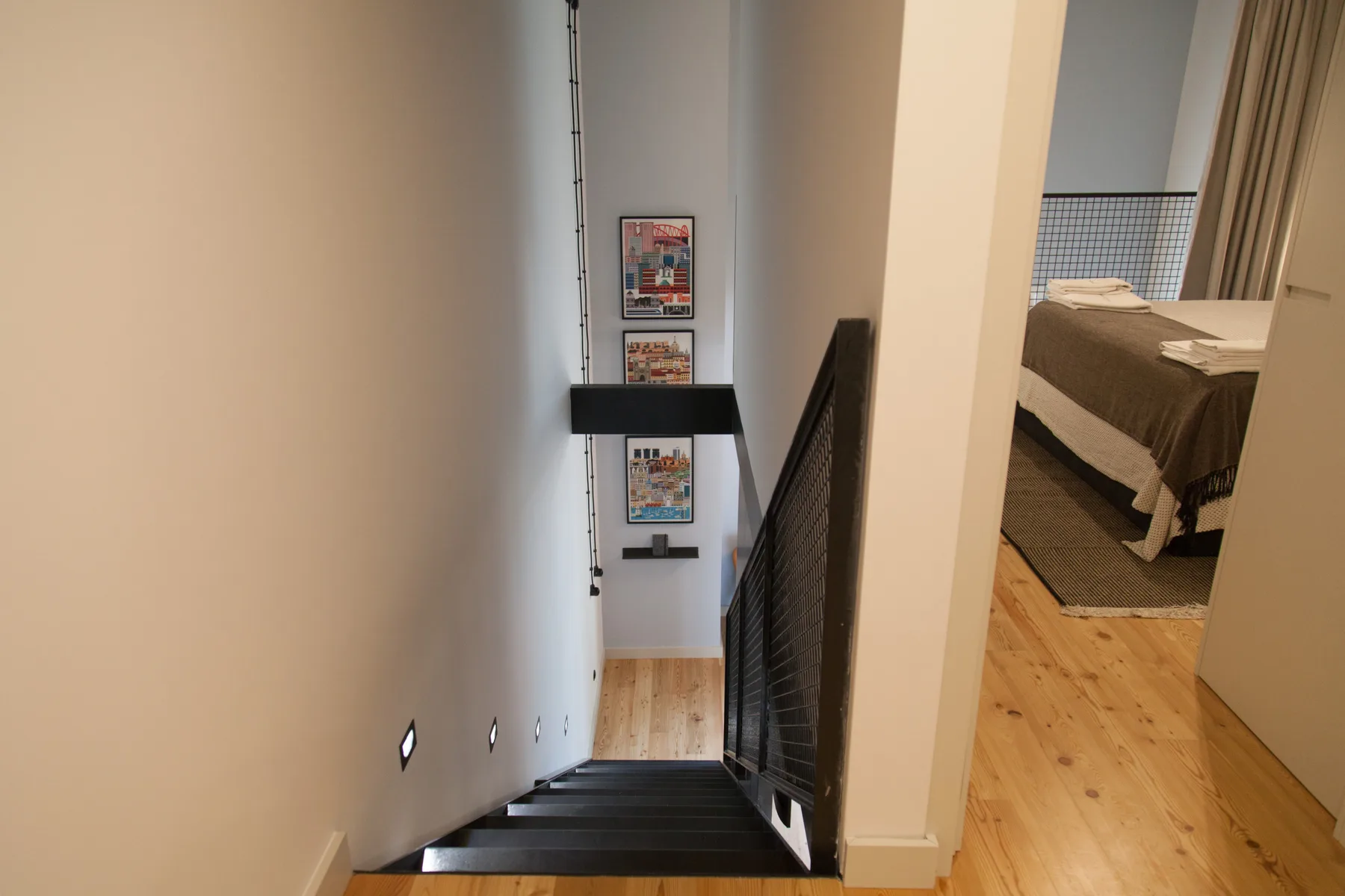 Una escalera interior estrecha baja junto a un dormitorio con una cama.
