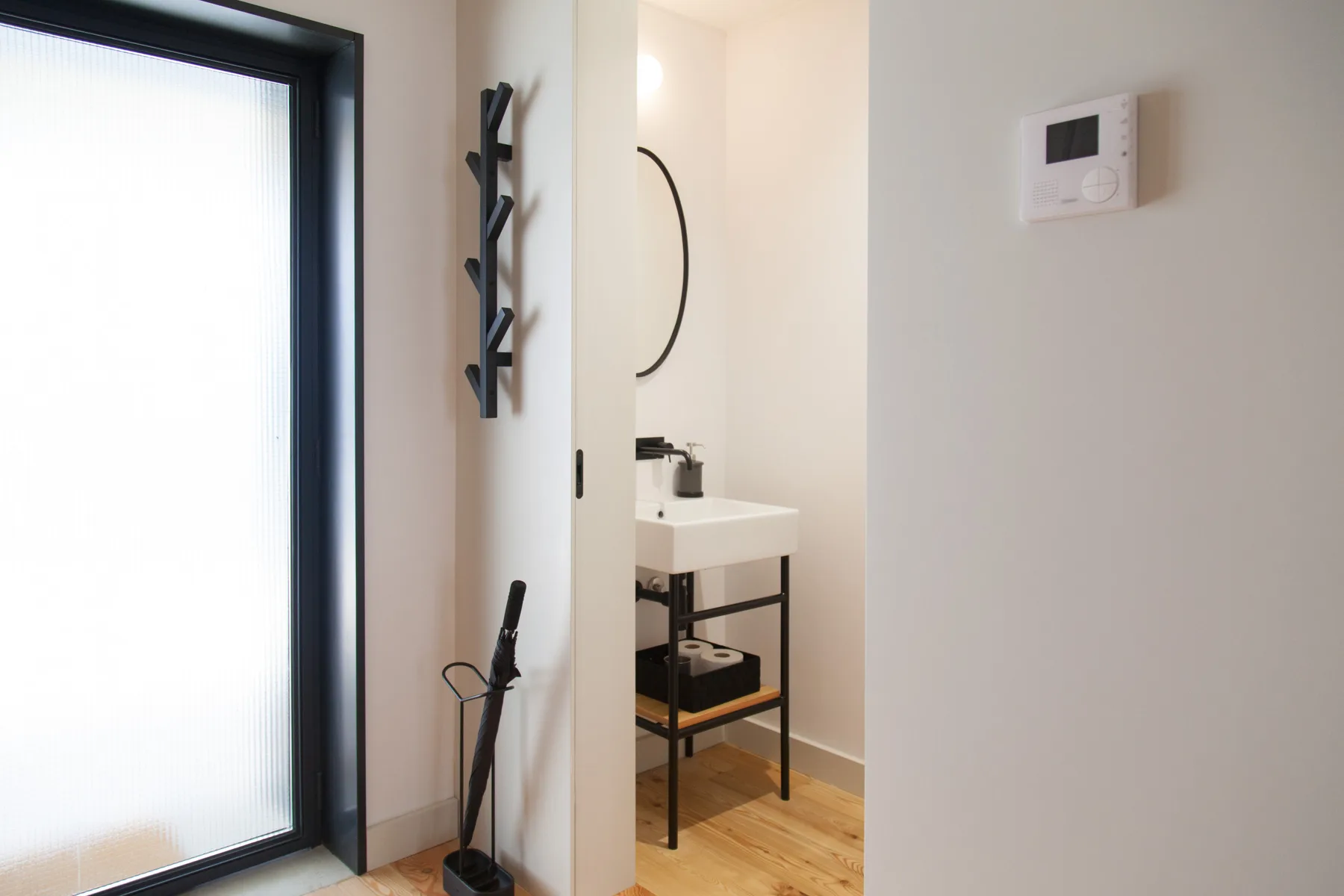 Se ve un lavabo en un pequeño rincón de baño junto a una puerta de vidrio esmerilado.