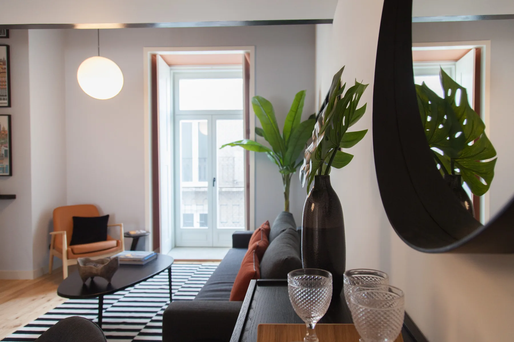 Una sala de estar con un sofá, una mesa de centro y plantas grandes en macetas.