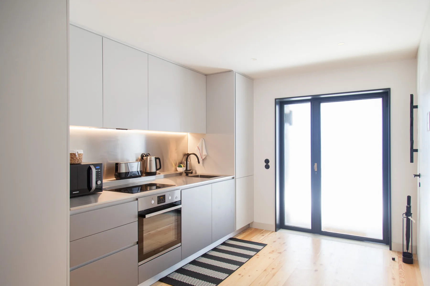 Una cocina moderna con electrodomésticos integrados y una puerta de vidrio grande.