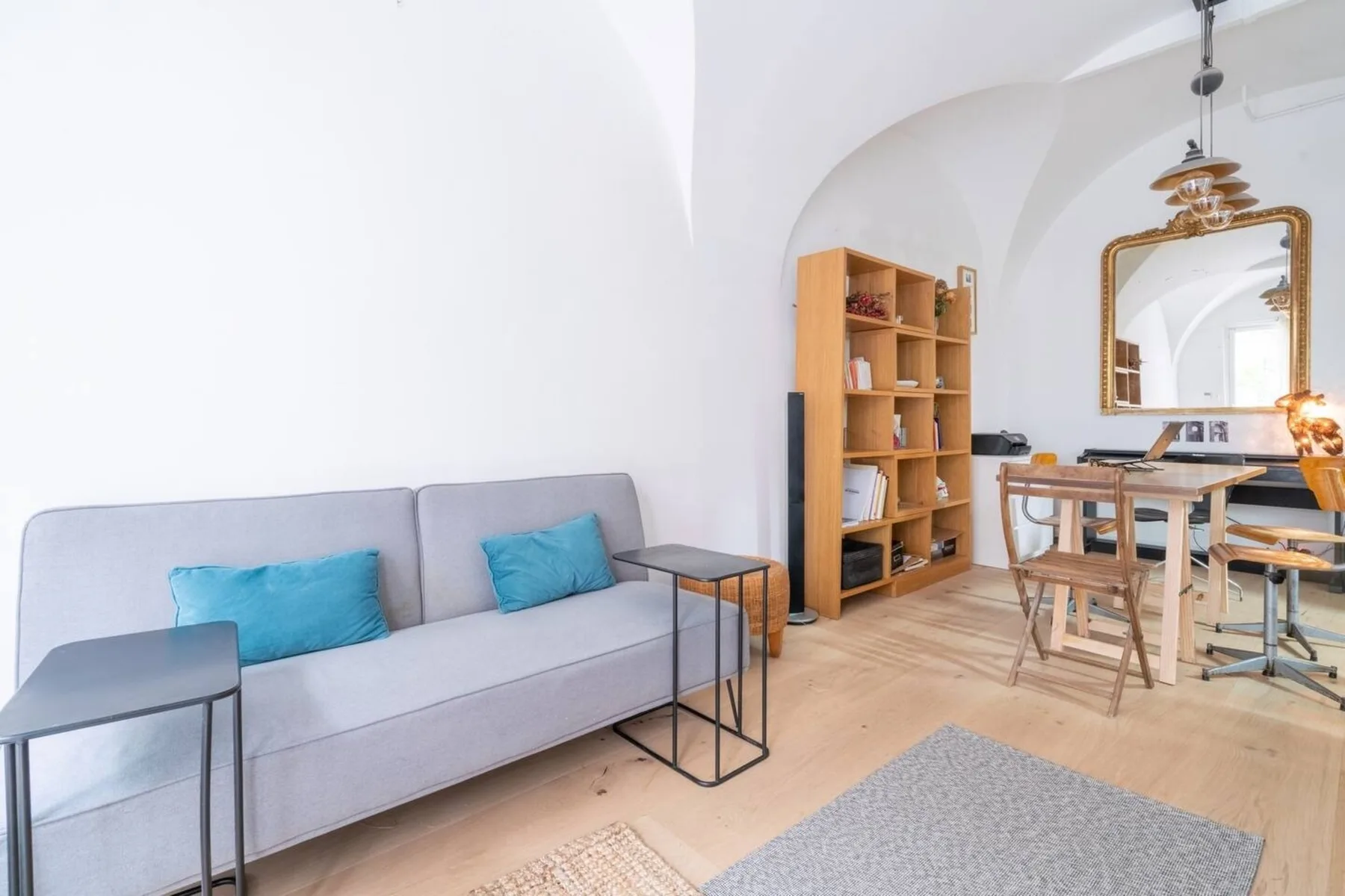 A bright living and dining area with a gray sofa and wooden table.