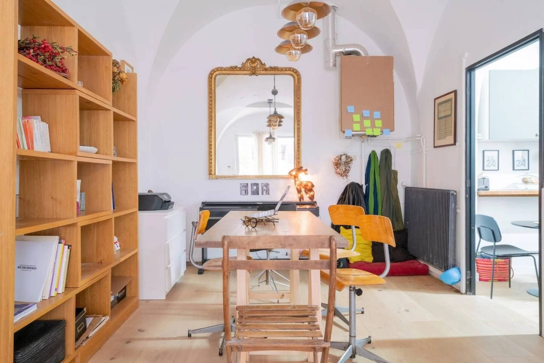 A dining and work area with a wooden table, chairs, and open shelving.
