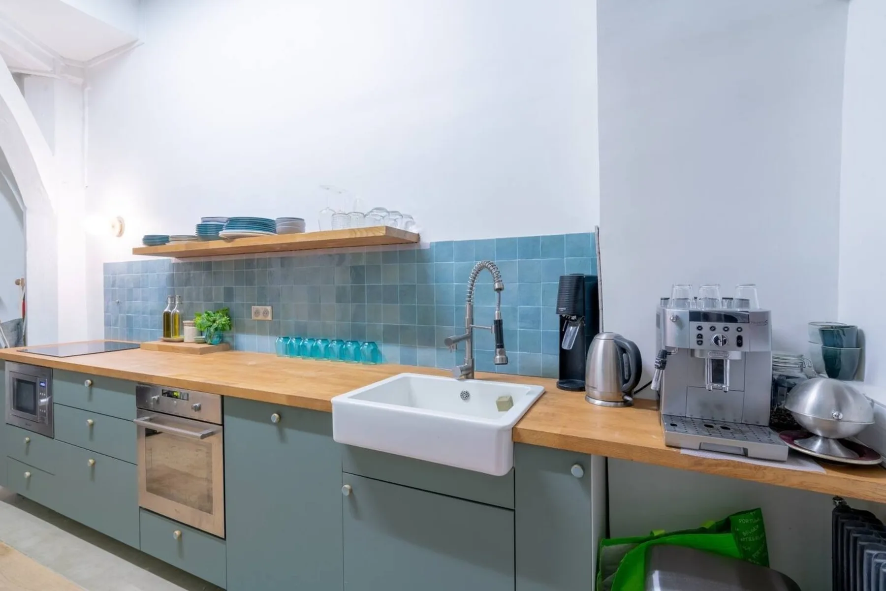 A kitchen counter with a sink, coffee machine, and blue tile backsplash.