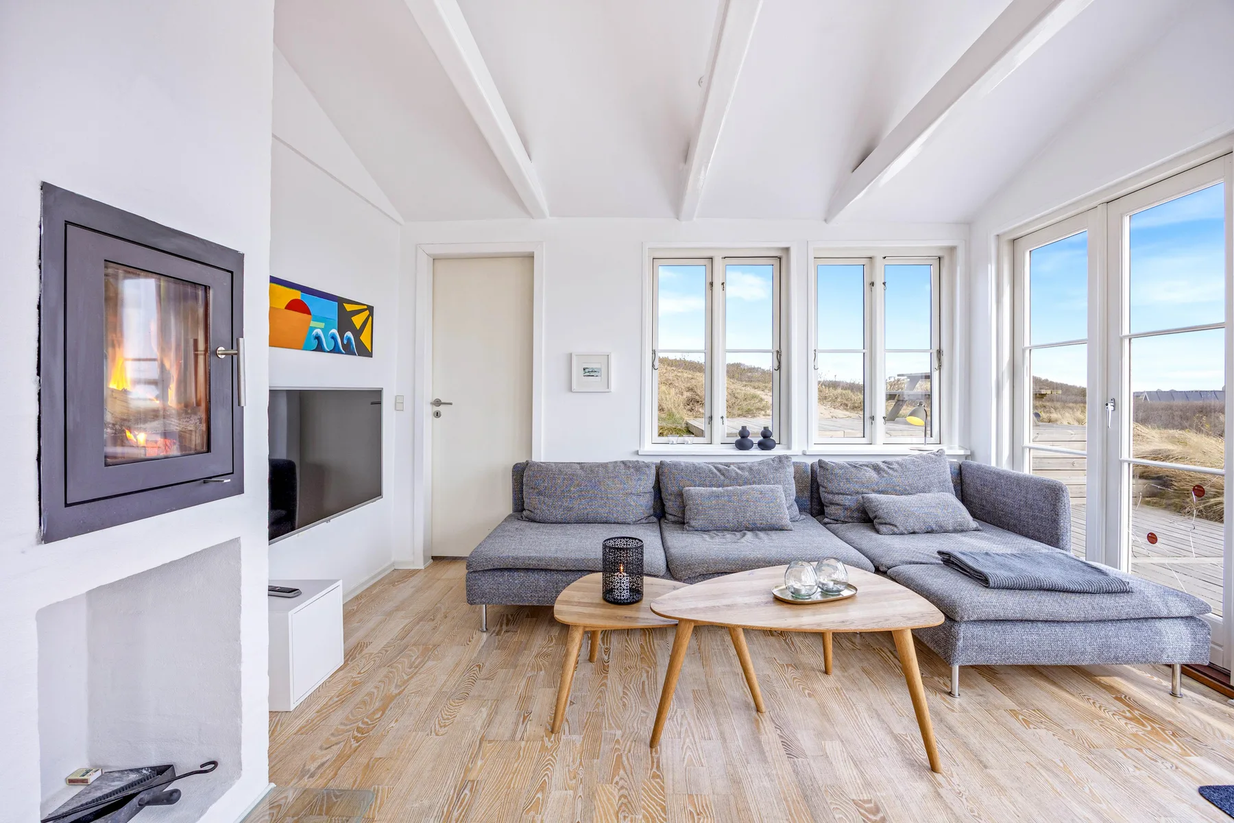 Una sala luminosa con asientos alrededor de una mesa de centro y grandes ventanas.