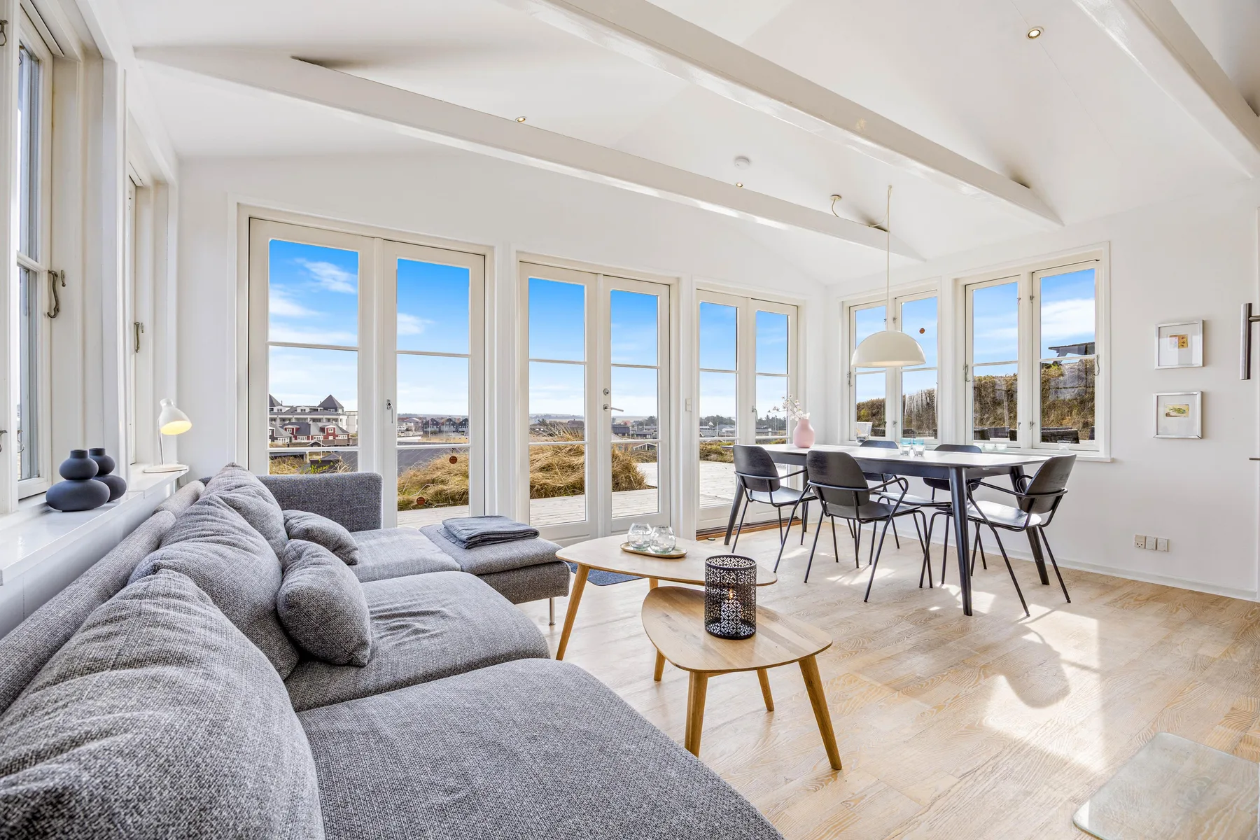 Una luminosa sala de estar y comedor con asientos junto a grandes ventanas.