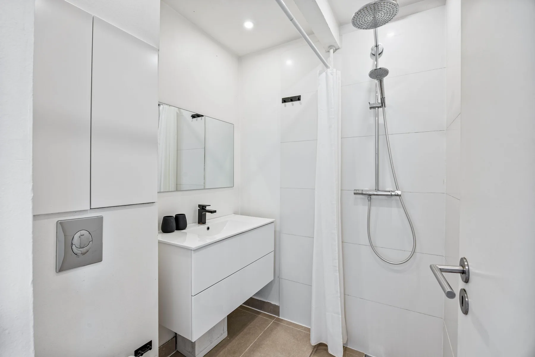 Un baño luminoso con lavabo, espejo y ducha.