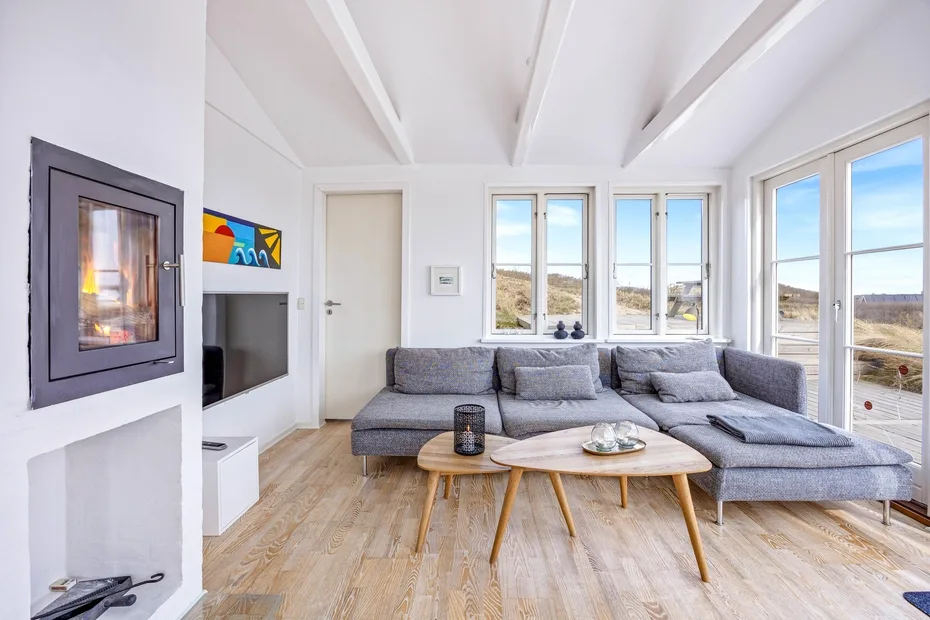 Una sala luminosa con asientos grises y grandes ventanales con vistas al paisaje.