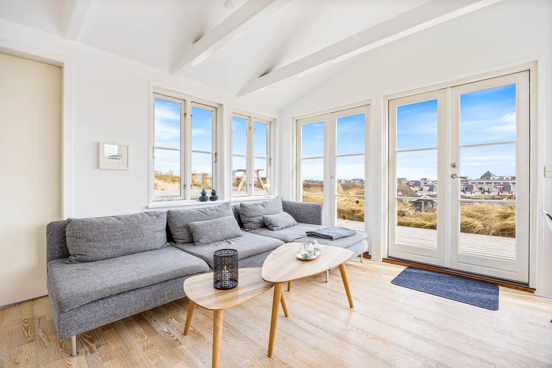 Una sala luminosa con asientos grises y grandes ventanas con vistas al paisaje.