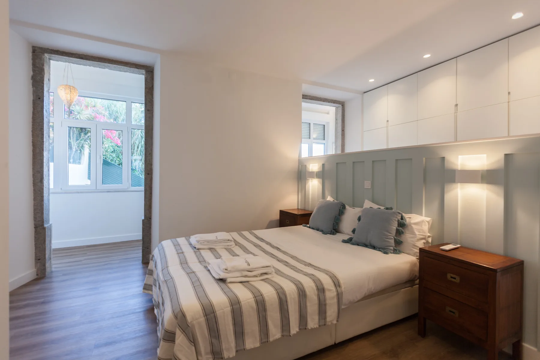 A bedroom with a bed beside a window and built-in cabinets.
