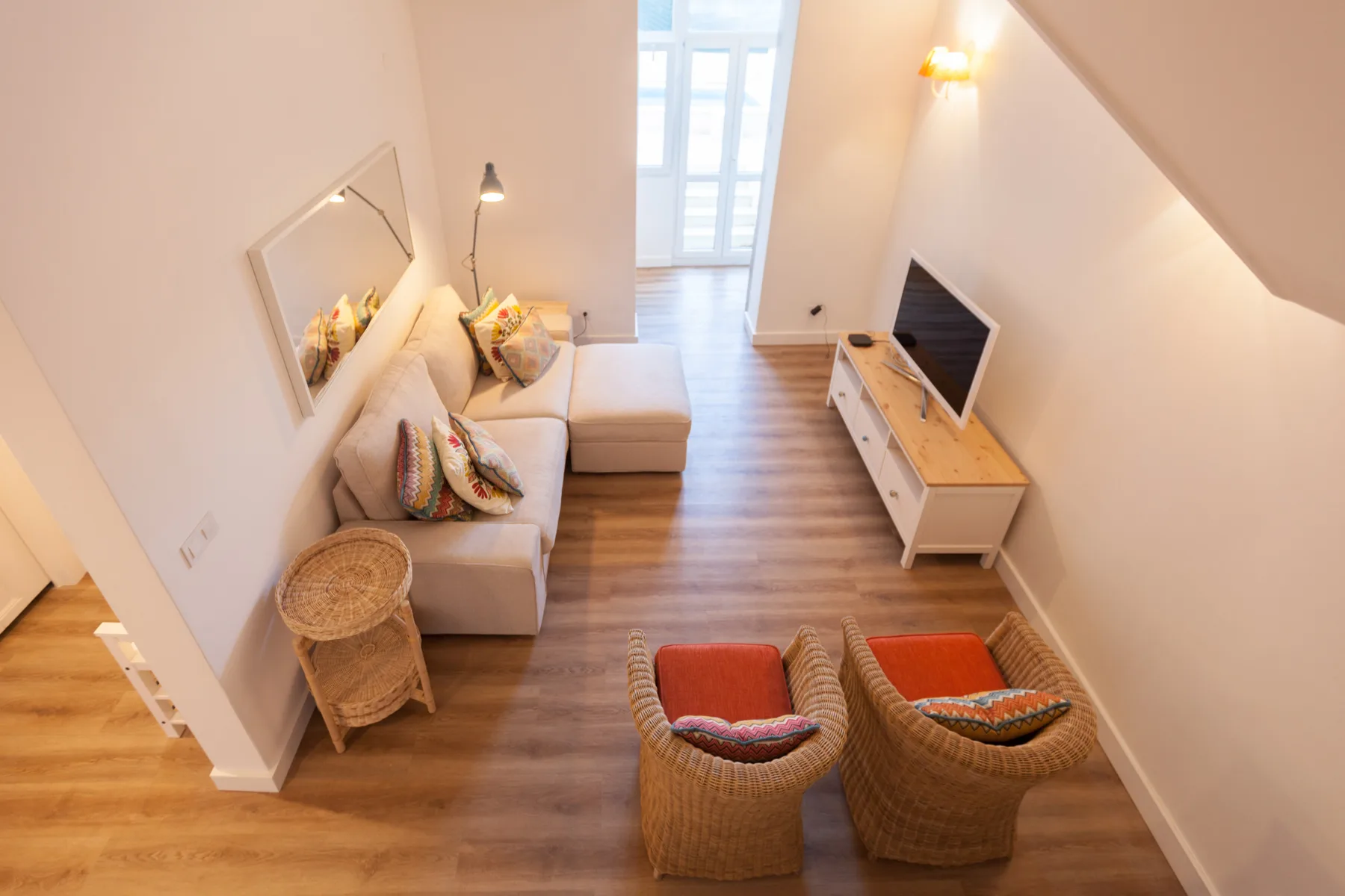 A living room with seating, a television, and wooden flooring.