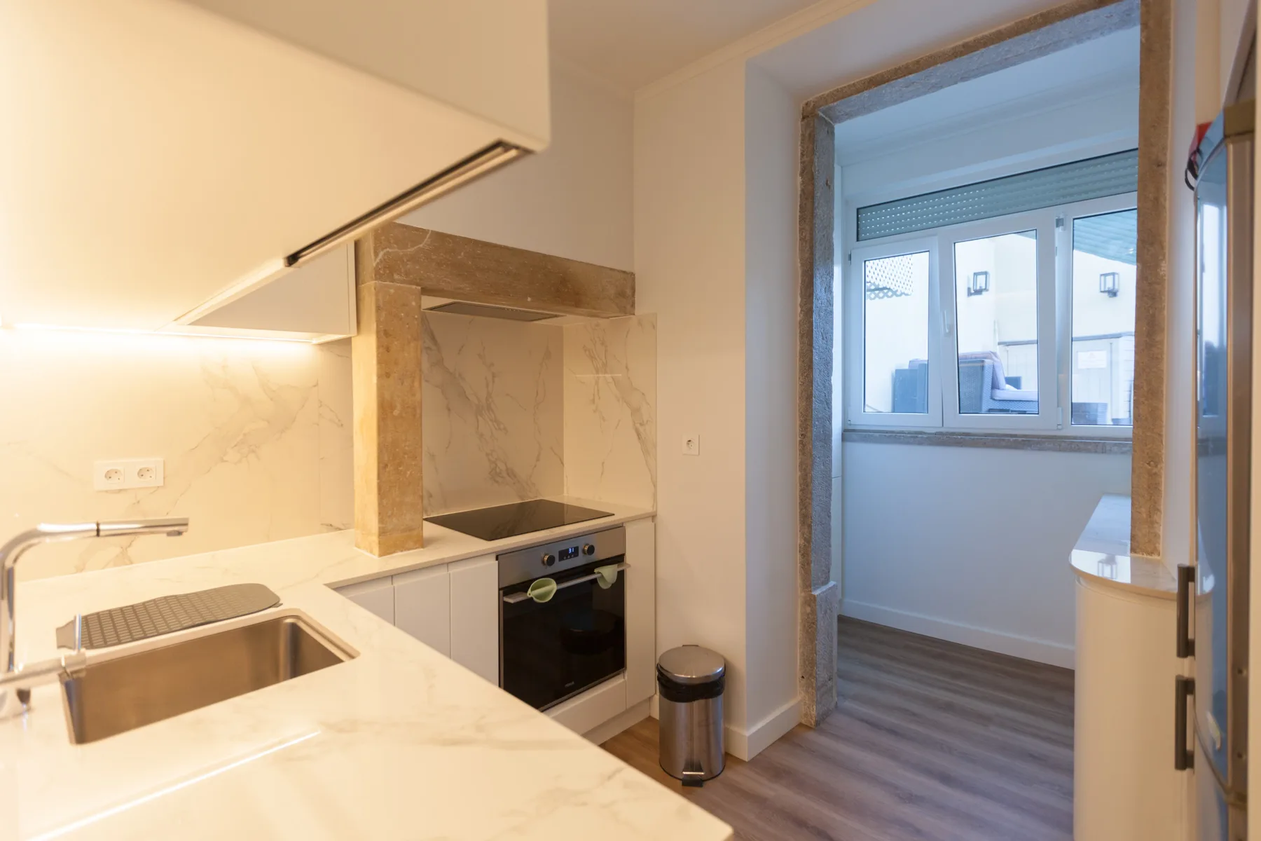 A compact kitchen opens onto a bright room with windows.