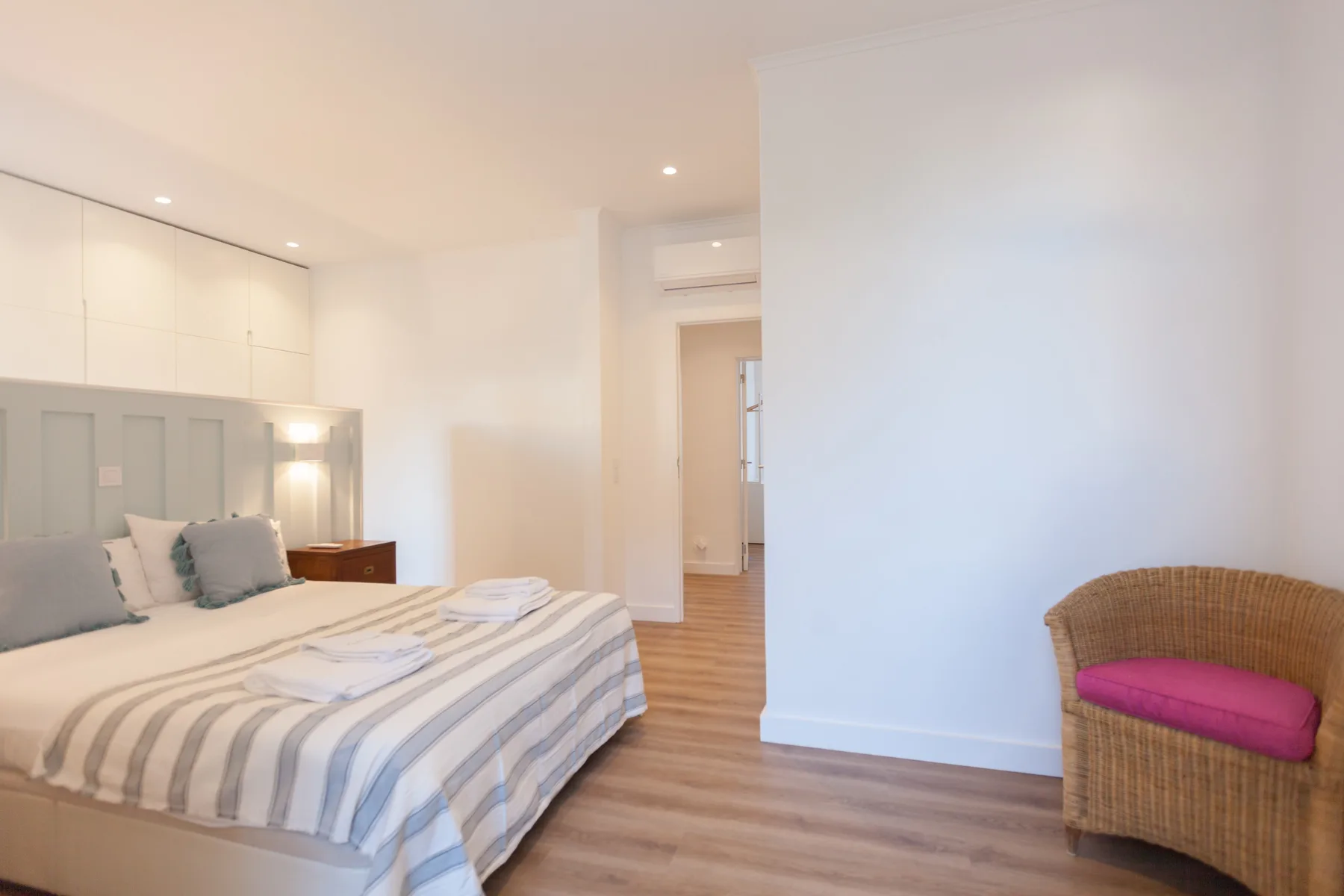 A bright bedroom with a bed and a wicker chair.