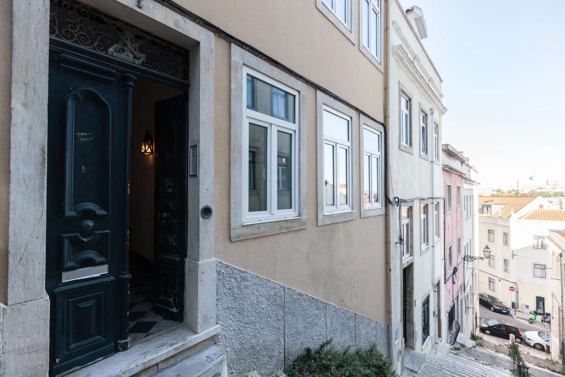 A narrow street slopes past a building entrance and neighboring facades.