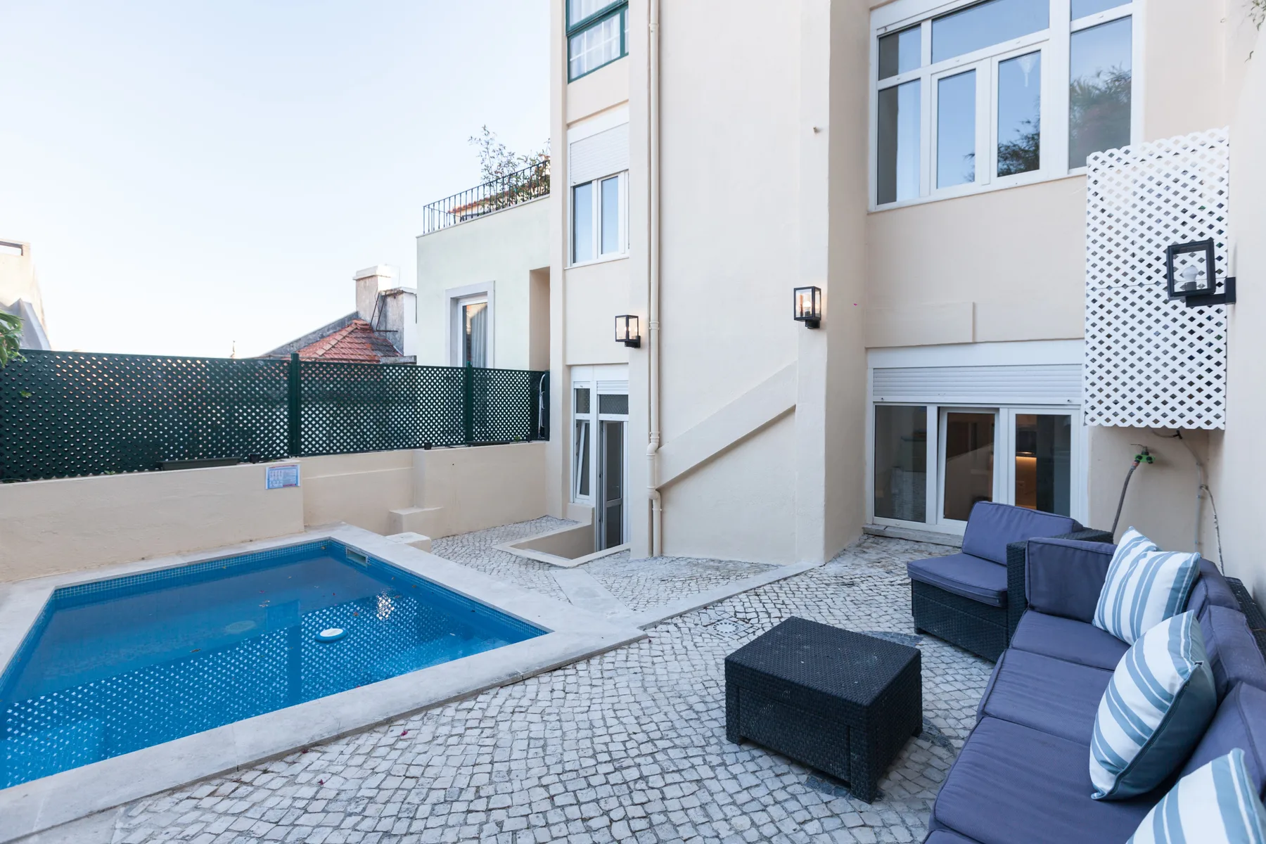 A paved courtyard features a small swimming pool and outdoor seating.