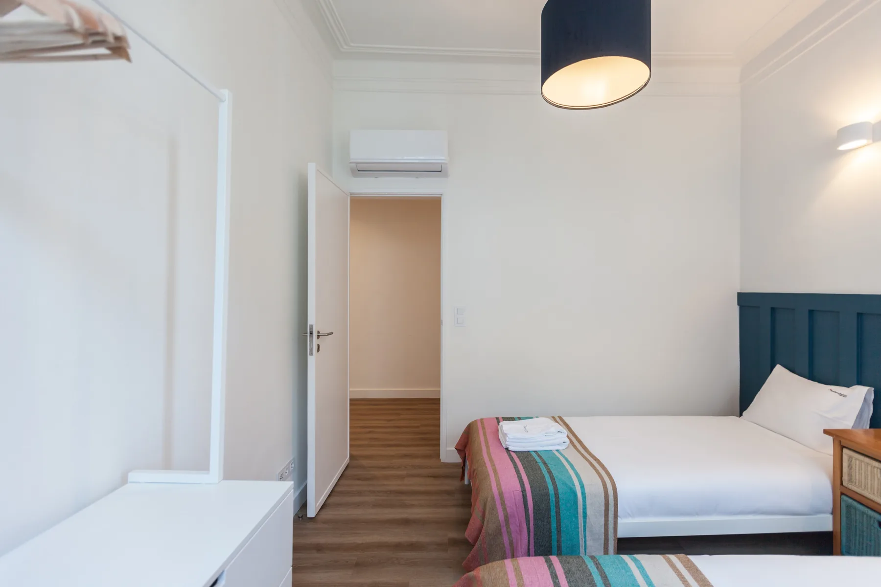 A bright bedroom with a bed and a doorway to the hall.