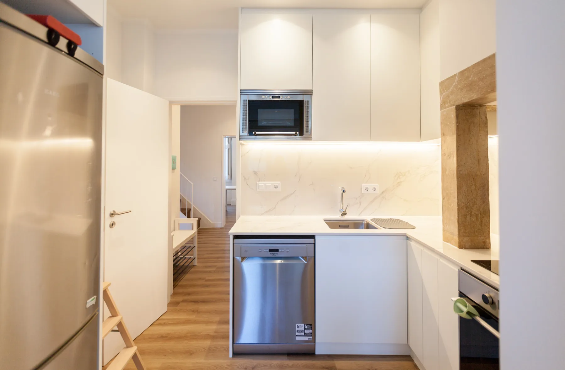 A bright kitchen with white cabinets, a sink, and stainless steel appliances.