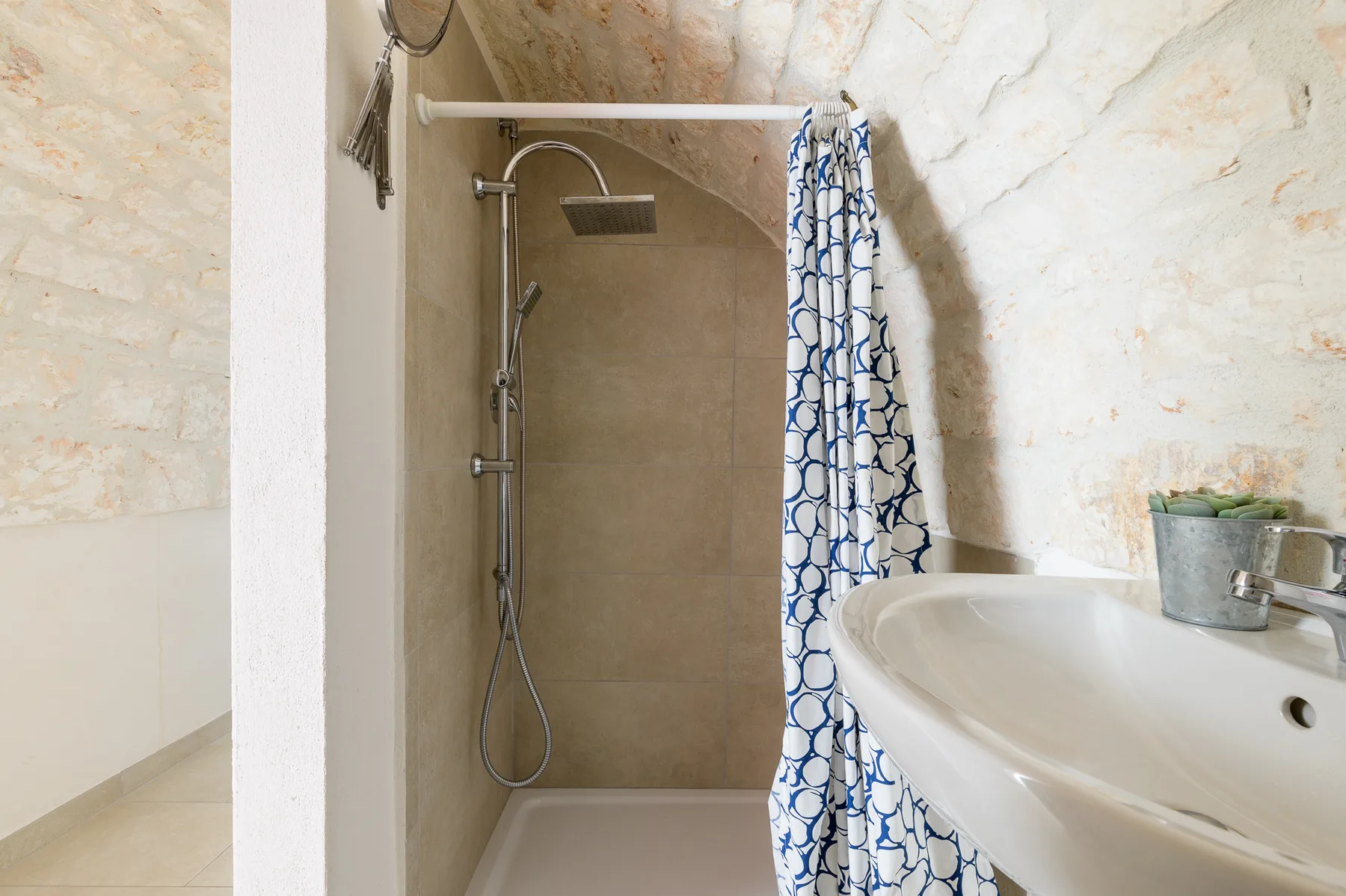 A bathroom with a shower and a white sink.