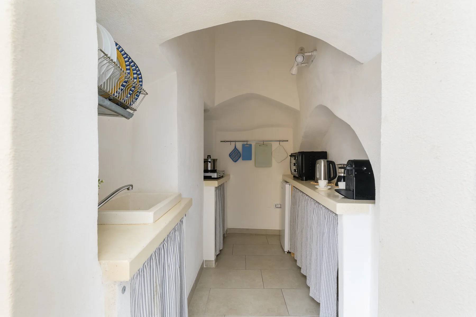 A narrow kitchen with counters on both sides and appliances at the back.