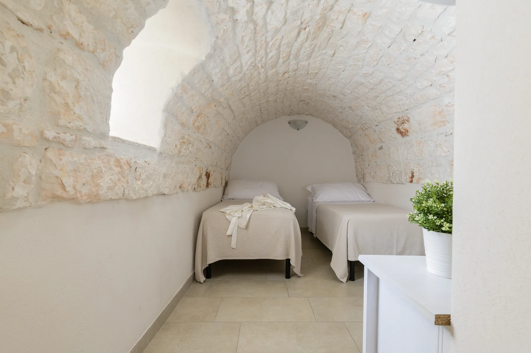 A bedroom with two beds beneath a vaulted stone ceiling.