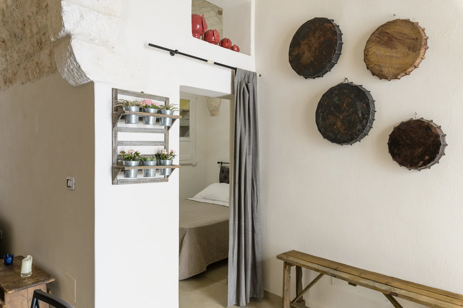 A bedroom is visible through a curtained doorway beside wall-mounted shelves.
