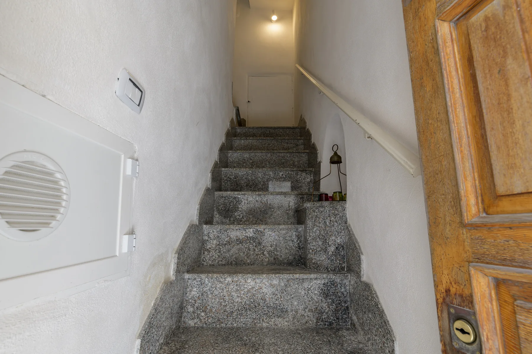 A narrow indoor stairwell with stone steps and white walls.