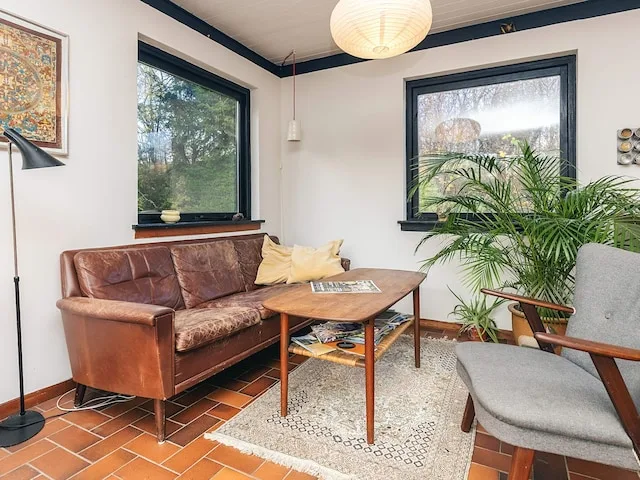 A living room with seating, a coffee table, and a large potted plant.