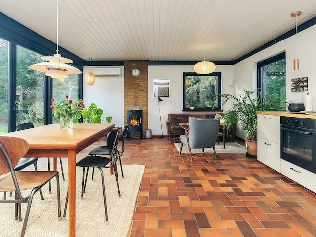 A dining and living area with a wooden table, seating, and a fireplace.