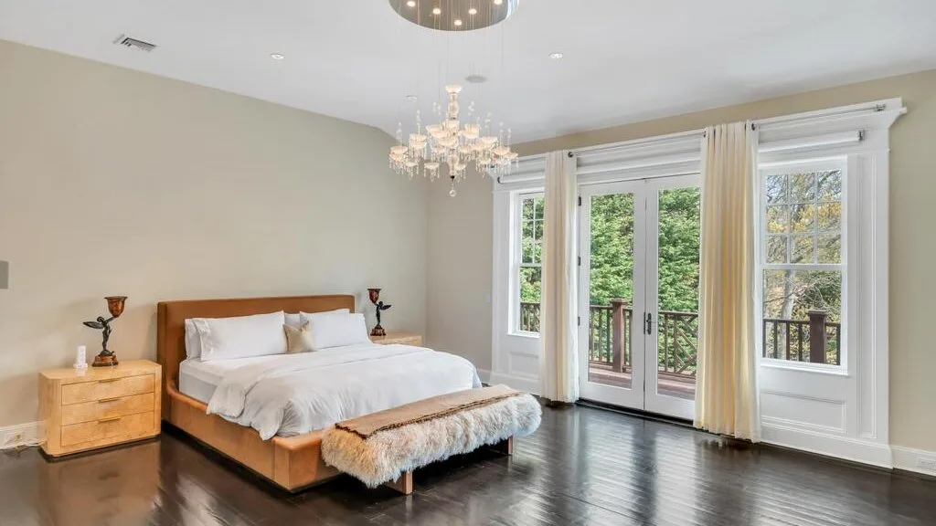 Un dormitorio con una cama junto a ventanas altas que dan a un balcón.