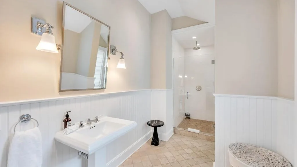 Un baño luminoso con lavabo y una zona de ducha al fondo.