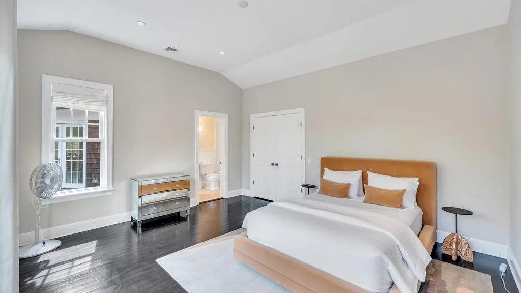 Un dormitorio con una cama, una ventana y una puerta blanca.