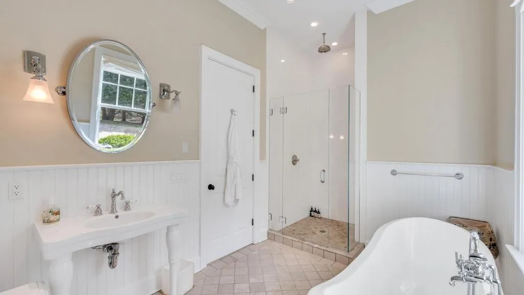 Un baño luminoso con lavabo, ducha de vidrio y bañera exenta.