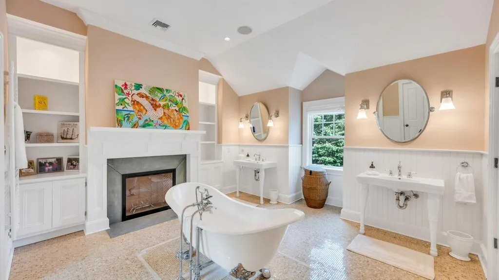 Un baño con bañera exenta, chimenea y lavabos dobles.