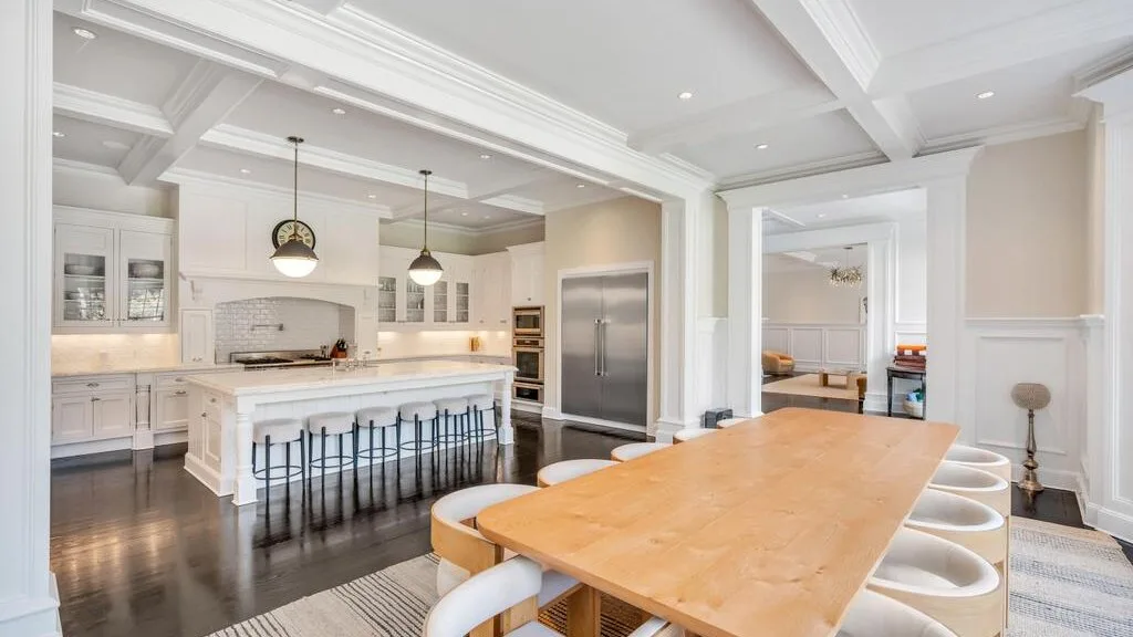 Una luminosa cocina y comedor con una gran mesa de madera y asientos junto a la isla.