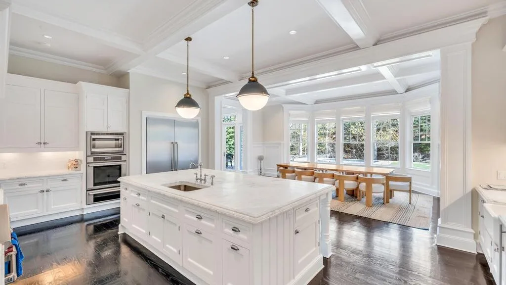 Una cocina luminosa con una gran isla central y una mesa de comedor junto a las ventanas.