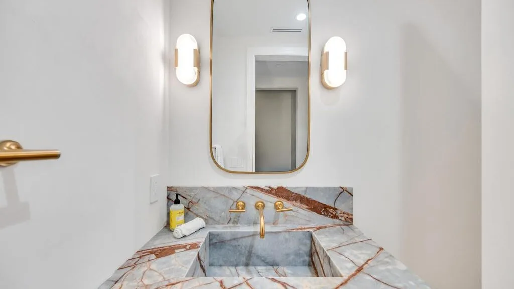 Un tocador de baño con encimera de piedra, lavabo y espejo.