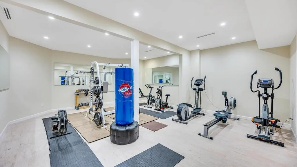 Un gimnasio interior luminoso con máquinas de ejercicio y un saco de boxeo azul.
