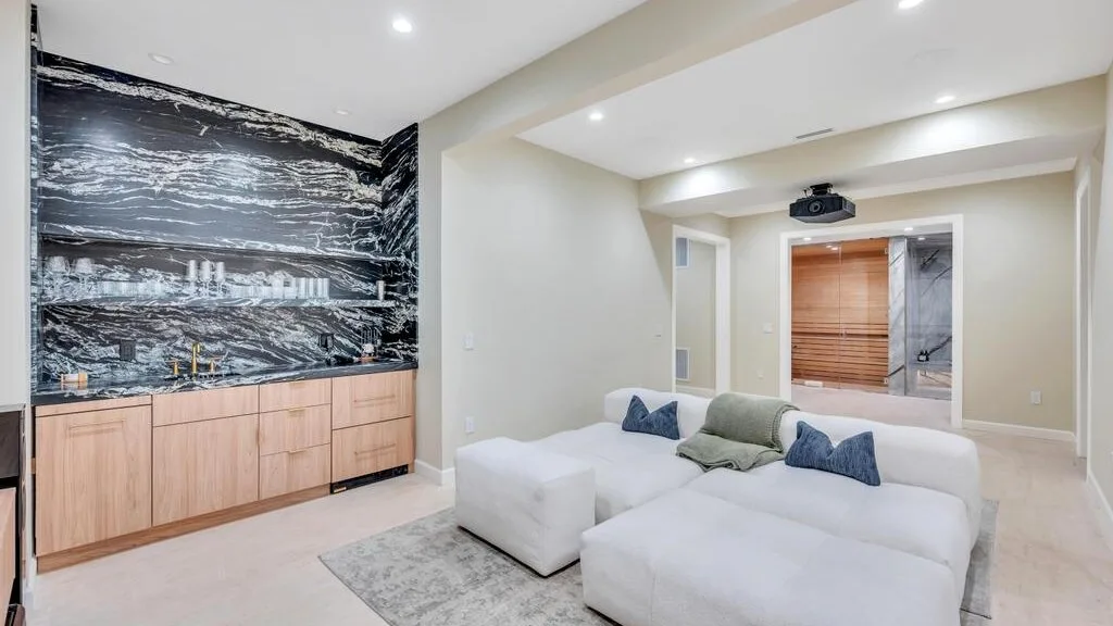 Una sala luminosa presenta asientos blancos y una pared con vetas oscuras.