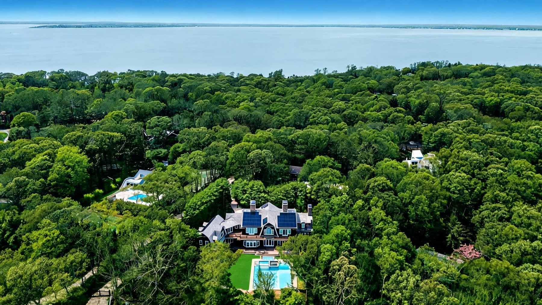 Una vista aérea muestra una casa y una piscina rodeadas de árboles frondosos.